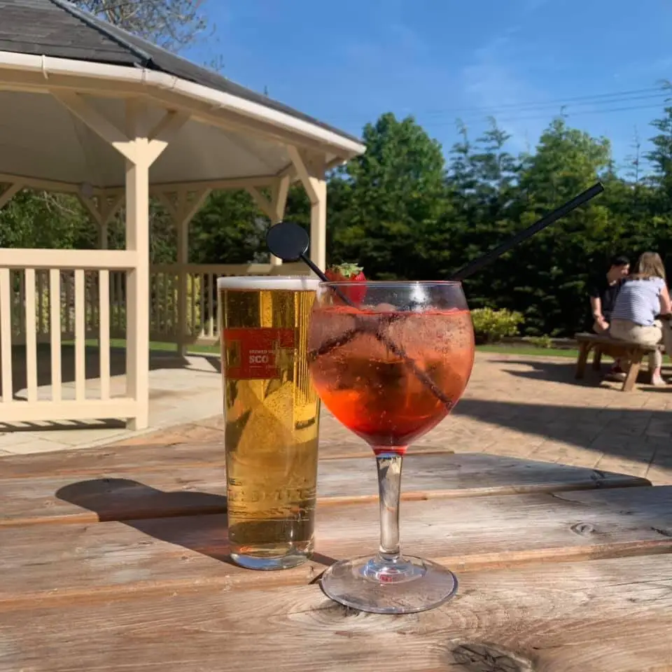 pint of beer and red drink with strawberry on wooden table